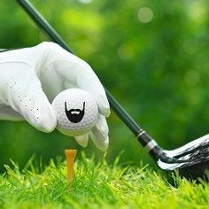 Golf ball printed with a black beard logo, held by a gloved hand